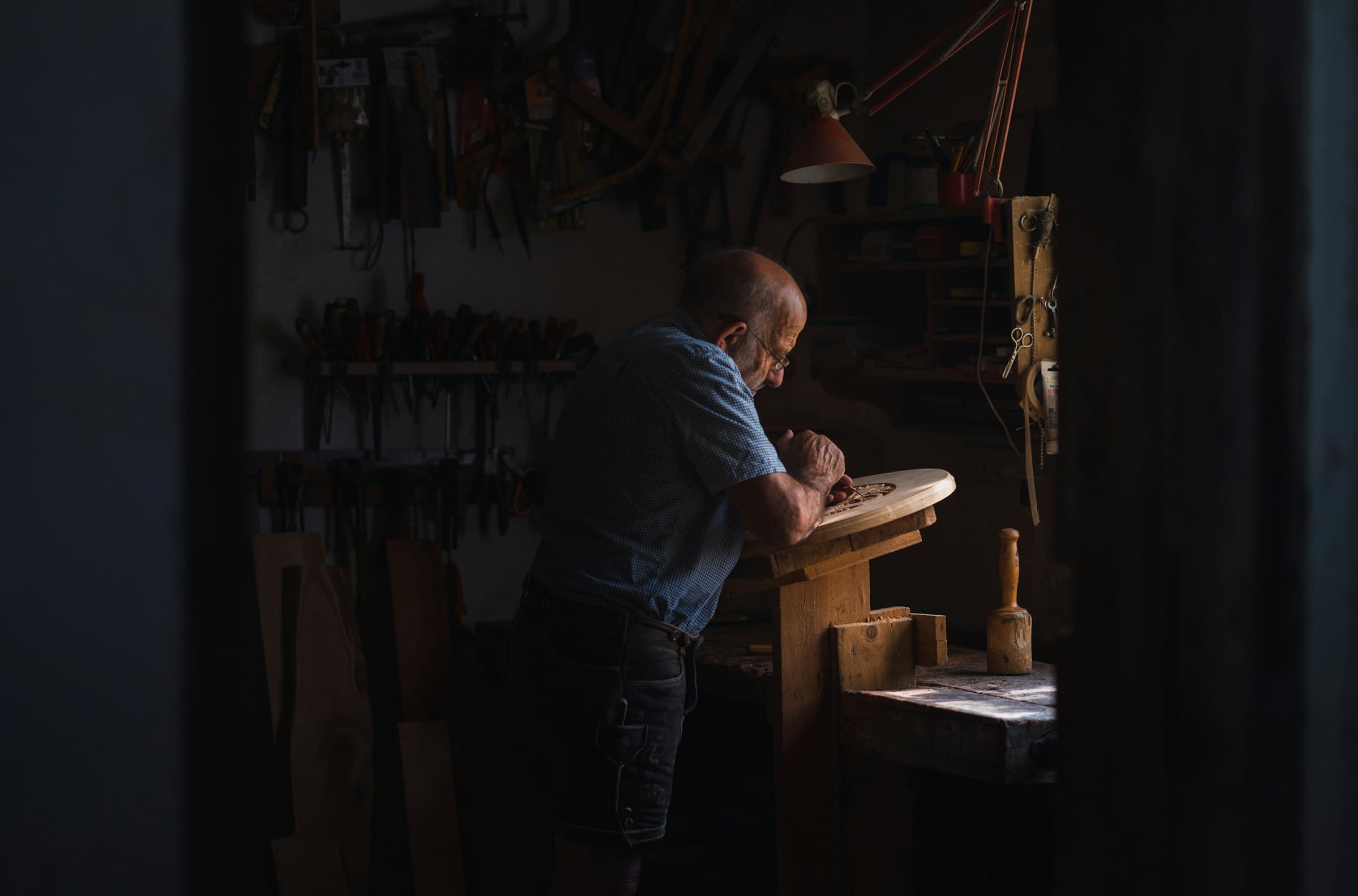 A woodworker carving a piece by hand in his workshop